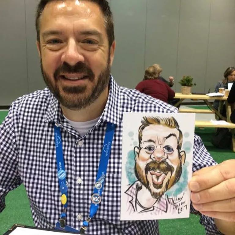 Guest holding a small printed caricature card drawn live at a conference